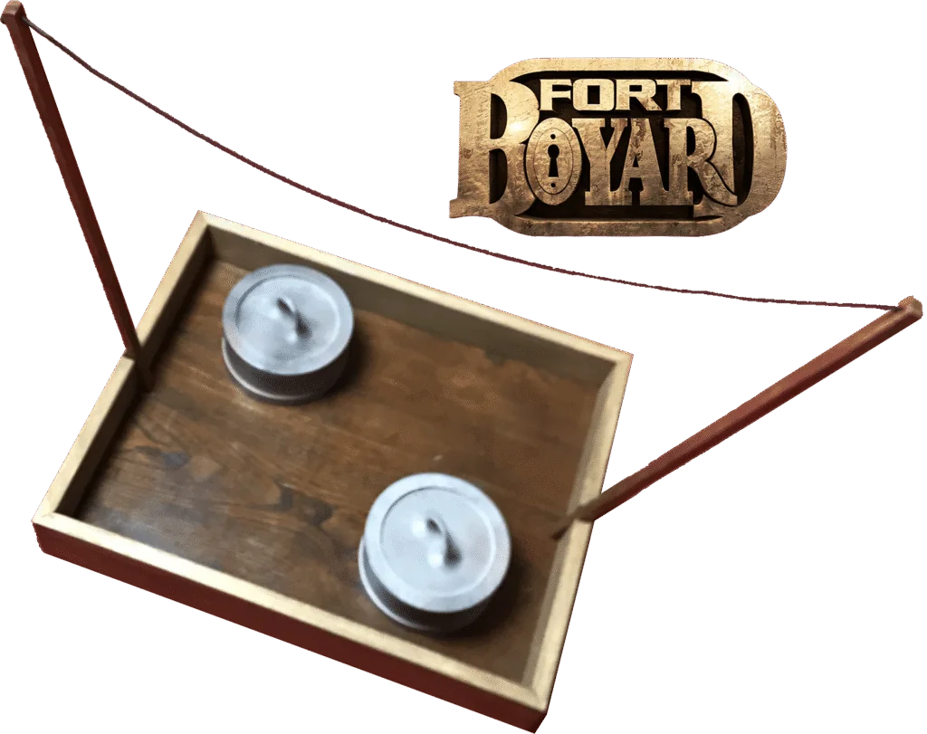 Jeu Les Poids, un duel de force du conseil de Fort Boyard, comprenant des poids et un fil tendu au-dessus de la table.