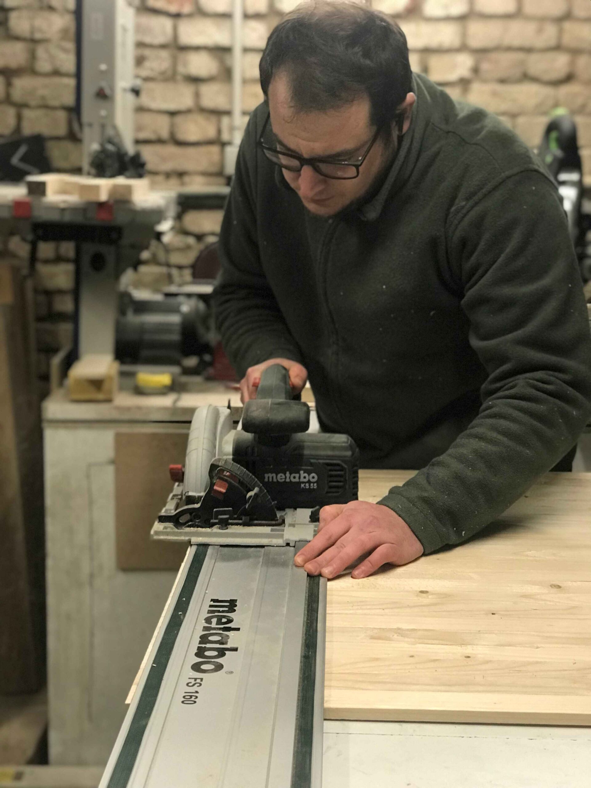 Artisan travaillant le bois avec une scie circulaire dans un atelier